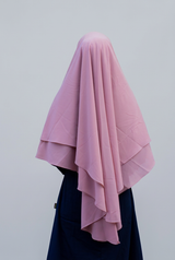 Roze Aliyah-khimar van achteren, met twee lagen en lange vallende plooien tegen een lichtgrijze achtergrond.